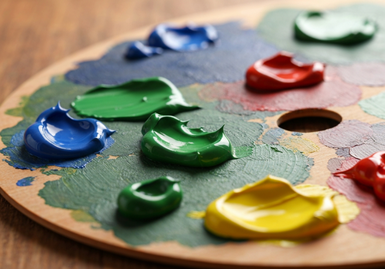 drewniana paleta malarska z grubymi plamami zielonej, niebieskiej, żółtej i czerwonej farby olejnej